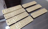 a collection of brass nameplates or plaques. Each plaque has a different word engraved on it.